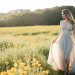 Uma mulher em pé em um campo de flores silvestres, a luz do sol lançando um brilho suave em seu cabelo enquanto uma brisa suave levanta a barra de seu vestido fluido.