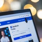 Uma tela de computador com um perfil do Facebook aberto, um cursor pairando sobre o botão "Excluir Conta", cercado por uma sensação de definitividade