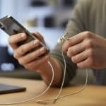 Mãos conectando fone com fio em um iPhone.