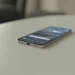 Celular moderno em uma superfície branca com o ícone de fone de ouvido conectado na tela.