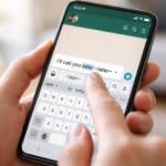 Pessoa segurando um smartphone mostrando uma conversa do WhatsApp com uma palavra riscada na mensagem sendo digitada.