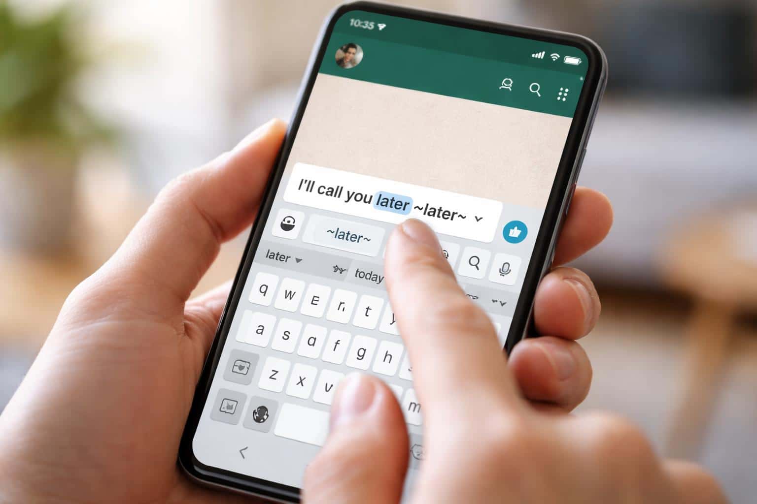 Pessoa segurando um smartphone mostrando uma conversa do WhatsApp com uma palavra riscada na mensagem sendo digitada.